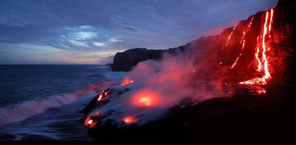 On Hawaii's Big Island, lava flows over a cliff and into the Pacific Ocean; this location is known as the Highcastle ocean entry. This is process by which the Hawaiian Islands are building up from the sea floor and creating new land. The flow is part of an eruption ongoing since May 2002, an eruption known in aggregate as the Mother's Day Flow, from  Pu'u 'O'o  crater of the Kilauea volcano in Hawaii Volcanoes National Park, Hawaii. The temperature of the lava is approximately 2100 degrees Fahrenheit. Steam clouds are water vapor mixed with hydrochloric acid.